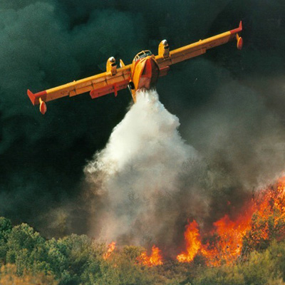 Aerial firefighter pouring water over a forest fire