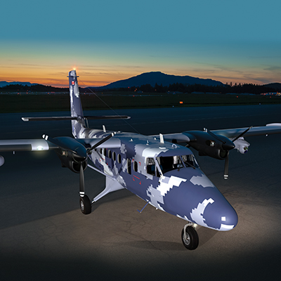 A dark camouflage Twin Otter Guardian aircraft on the runway