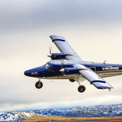 Twin Otter aircraft in flight over the mountains