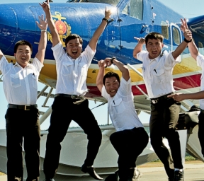 Group of pilots cheering in front of Twin Otter aircraft