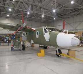 Dark green Twin Otter aircraft in hangar