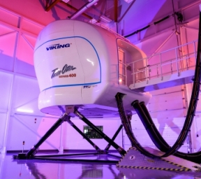 Flight simulator pod standing in purple-hued hangar
