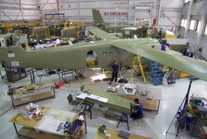 Two aircraft and several technicians inside a large hangar